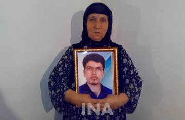 La mère de Farzad Kamangar, tenant son portrait.