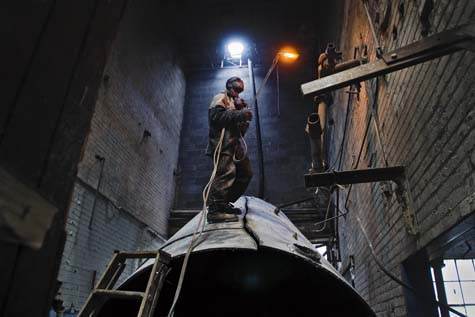 A young man is cutting metal in an old industrial plant to sell it on the metal yard. A young man is cutting metal in an old industrial plant to sell it on the metal yard.
