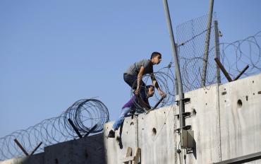Des Palestiniens escaladent le mur de séparation le 4 juillet. Des Palestiniens escaladent le mur de séparation le 4 juillet.