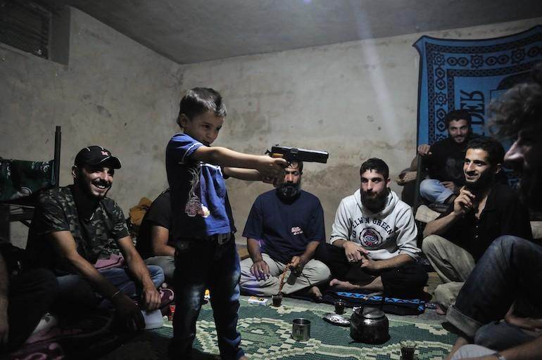 Moment de détente entre compagnons de guerre. Un enfant joue au moudjahidine sous le regard de ses aînés. Moment de détente entre compagnons de guerre. Un enfant joue au moudjahidine sous le regard de ses aînés.