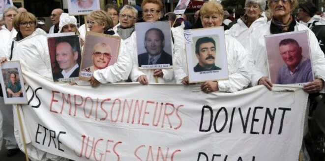 Des manifestants brandissent des portraits de victimes de l'amiante, en février 2013 à Paris © Reuters