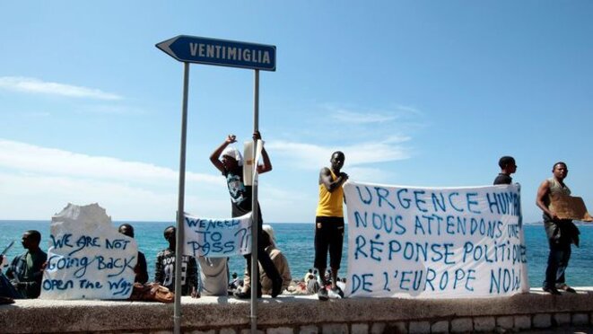 a-group-of-migrants-shout-slogans-and-display-a-banner-at-the-saint-ludovic-border-crossing-on-the-mediterranean-sea-between-vintimille-italy-and-menton-5359265