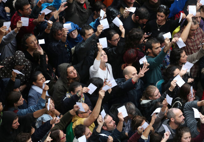 Des Catalans tenant leur bulletin de vote devant un bureau © Reuters