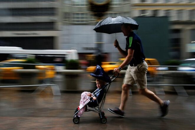Un homme court sous la pluie avec son enfant à Manhattan, août 2016. © Eduardo Munoz/Reuters Un homme court sous la pluie avec son enfant à Manhattan, août 2016. © Eduardo Munoz/Reuters