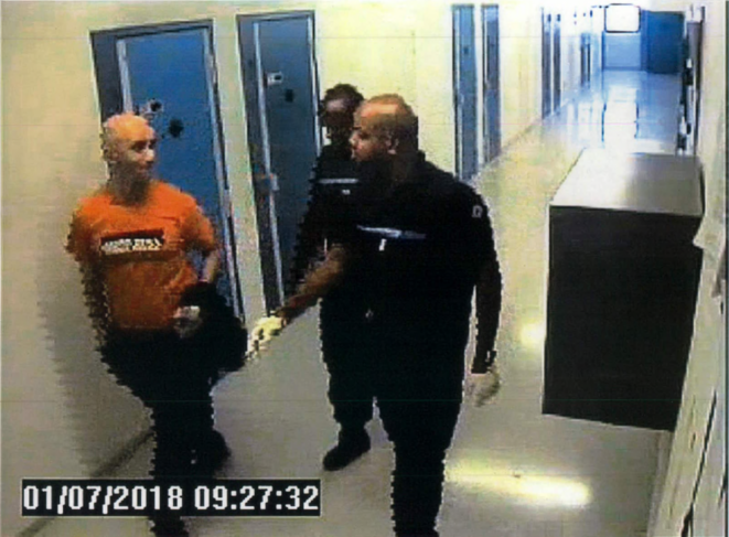 Redoine Faïd, en T-shirt orange, escorté par des surveillants jusqu’au parloir, deux heures avant son évasion. © DR Redoine Faïd, en T-shirt orange, escorté par des surveillants jusqu’au parloir, deux heures avant son évasion. © DR