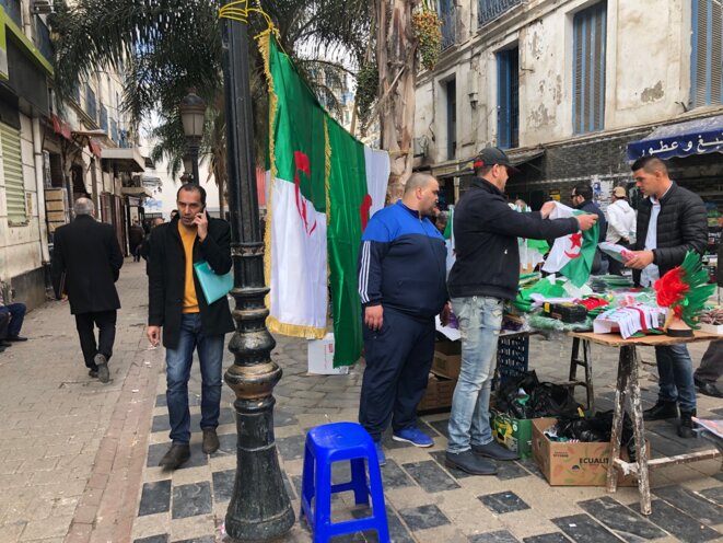 Partout dans la ville, des vendeurs de drapeaux, foulards, écharpes, bracelets, perruques aux couleurs de l’Algérie, emblèmes des manifestants criant le slogan « Un héros, le peuple, c’est notre pays ». © LB Partout dans la ville, des vendeurs de drapeaux, foulards, écharpes, bracelets, perruques aux couleurs de l’Algérie, emblèmes des manifestants criant le slogan « Un héros, le peuple, c’est notre pays ». © LB