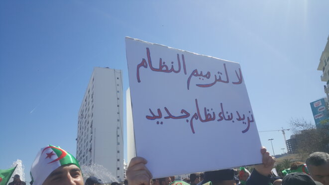 La pancarte se lit comme suit: «Non à la réforme du régime, Nous voulons en construire un nouveau. »Photo prise à Alger le vendredi 15 mars 2019. © hamza hamouchene La pancarte se lit comme suit: «Non à la réforme du régime, Nous voulons en construire un nouveau. »Photo prise à Alger le vendredi 15 mars 2019. © hamza hamouchene