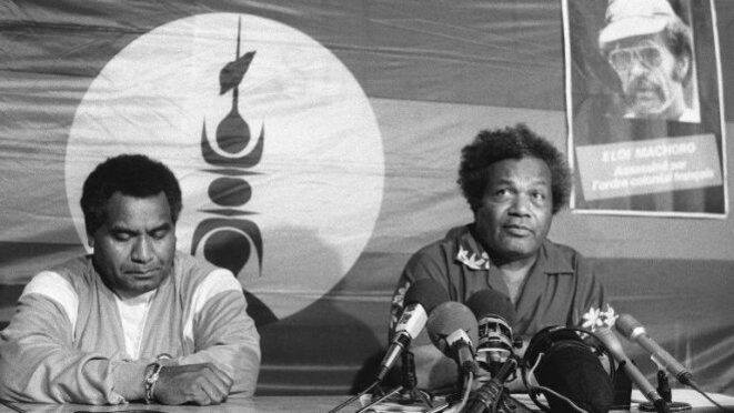Tjibaou et Yeiwéné quelques mois avant leur assassinat. A coté du drapeau Kanaky, un poster d'Eloi Machoro "assassiné par l'ordre colonial francais". Tjibaou et Yeiwéné quelques mois avant leur assassinat. A coté du drapeau Kanaky, un poster d'Eloi Machoro "assassiné par l'ordre colonial francais".