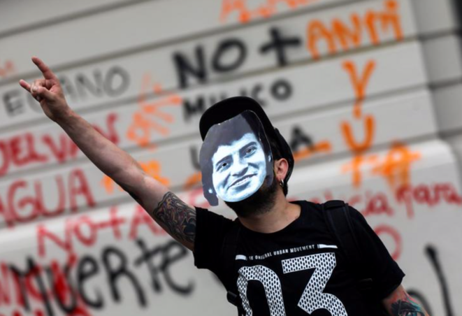 Un manifestant porte un masque de Víctor Jara à Santiago (Chili) le 29 octobre 2019. © REUTERS/Edgard Garrido Un manifestant porte un masque de Víctor Jara à Santiago (Chili) le 29 octobre 2019. © REUTERS/Edgard Garrido