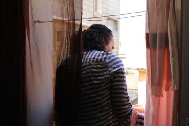 Samia, 39 ans, jette un œil par la fenêtre de son appartement, dans le quartier de Miramar à Oran. © NB