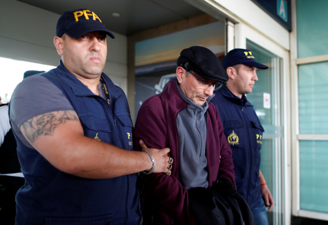 Mario Sandoval escorted by police on his arrival at Buenos Aires airport after extradition from France. © Reuters