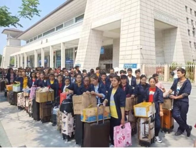 Des travailleurs ouïghours de la société Hubei Yihong Precision Manufacturing Co. Ltd lors de leur transfert entre le Xinjiang et Xianning, Hubei. Cette photo a été prise devant la gare de Wuchang à Wuhan, la capitale provinciale de Hubei, en mai 2018. Des travailleurs ouïghours de la société Hubei Yihong Precision Manufacturing Co. Ltd lors de leur transfert entre le Xinjiang et Xianning, Hubei. Cette photo a été prise devant la gare de Wuchang à Wuhan, la capitale provinciale de Hubei, en mai 2018.