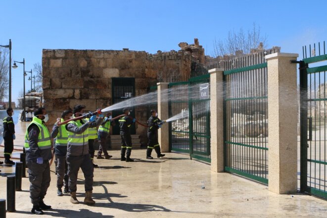 Des soldats libanais désinfectent l'entrée du site historique de Baalbek le 16 mars 2020. © AFP