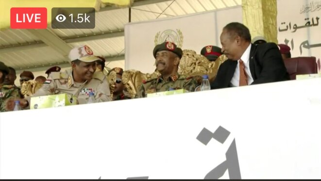 Le Premier Ministre Abdalla Hamdok et le Chef des RSF Hemetti s'amusent et blaguent ensemble pendant la cérémonie des RSF du 7 mars 2020. Capture d'écran de la retransmission vidéo de la cérémonie. Le Premier Ministre Abdalla Hamdok et le Chef des RSF Hemetti s'amusent et blaguent ensemble pendant la cérémonie des RSF du 7 mars 2020. Capture d'écran de la retransmission vidéo de la cérémonie.