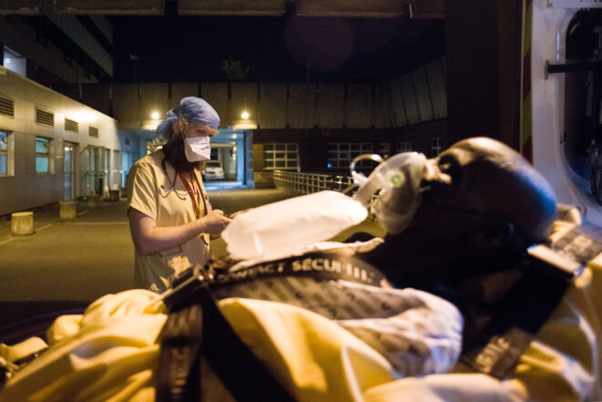 Des bénévoles de la protection civile transfèrent des patients infectés par le COVID 19 et ayant des problèmes respiratoires dans les hôpitaux parisien © AFP