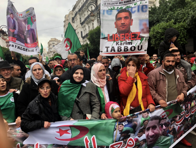 Zahra, l'épouse de Karim Tabbou, voile rose pastel et blanc, et leurs enfants ouvrent en famille le cortège de soutien appelant à la libération de son mari lors d'un vendredi de manifestation à Alger, en novembre 2019. © Kahina Nour