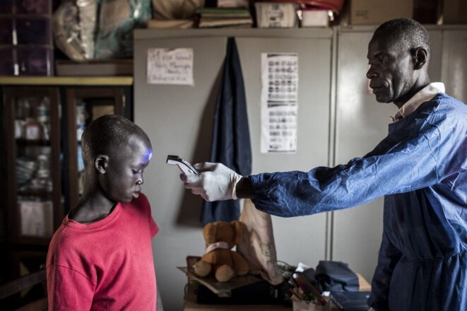 Un enfant de rue accueilli dans un centre à Dakar se voit prendre sa température le 10 avril 2020. © John Wessels/AFP