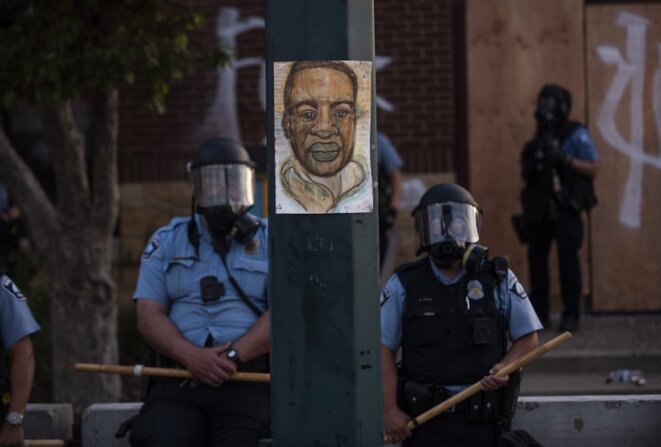 27 mai 2020, Minneapolis, États-Unis. Un portrait de George Floyd entre deux policiers durant une manifestation. © Stephen Maturen/Getty Images/AFP 27 mai 2020, Minneapolis, États-Unis. Un portrait de George Floyd entre deux policiers durant une manifestation. © Stephen Maturen/Getty Images/AFP