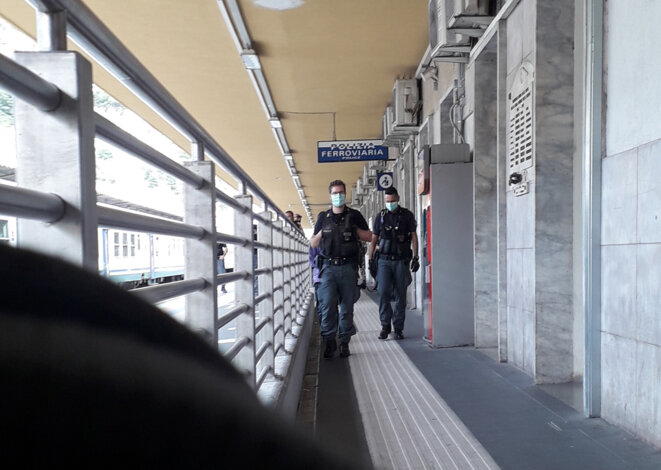 Deux policiers italiens « escortent » un jeune homme noir sur le quai de la gare de Vintimille, le jeudi 11 juin 2020. © Morgane Dujmovic Deux policiers italiens « escortent » un jeune homme noir sur le quai de la gare de Vintimille, le jeudi 11 juin 2020. © Morgane Dujmovic