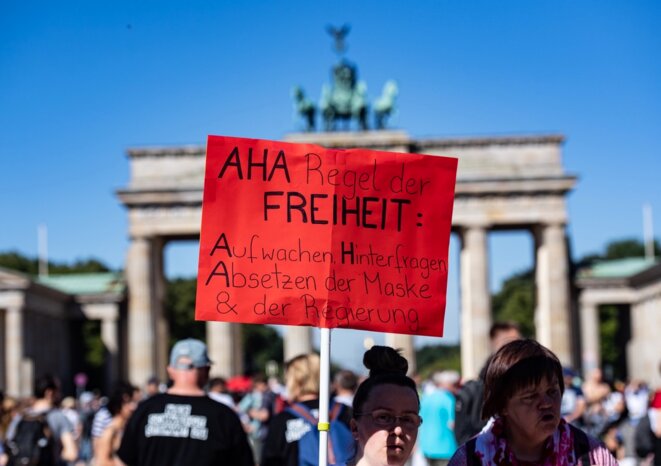 Manifestation à Berlin contre les mesures covid d'A. Merkel. Traduction affiche : Règles de liberté : se réveiller, questionner, retirer le masque et le gouvernement Manifestation à Berlin contre les mesures covid d'A. Merkel. Traduction affiche : Règles de liberté : se réveiller, questionner, retirer le masque et le gouvernement