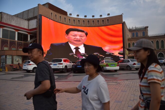 Des passants devant un écran montrant le président chinois Xi Jinping à Kachgar, ville de la région autonome ouïghoure du Xinjiang, en juin 2019. © Greg Baker / AFP Des passants devant un écran montrant le président chinois Xi Jinping à Kachgar, ville de la région autonome ouïghoure du Xinjiang, en juin 2019. © Greg Baker / AFP
