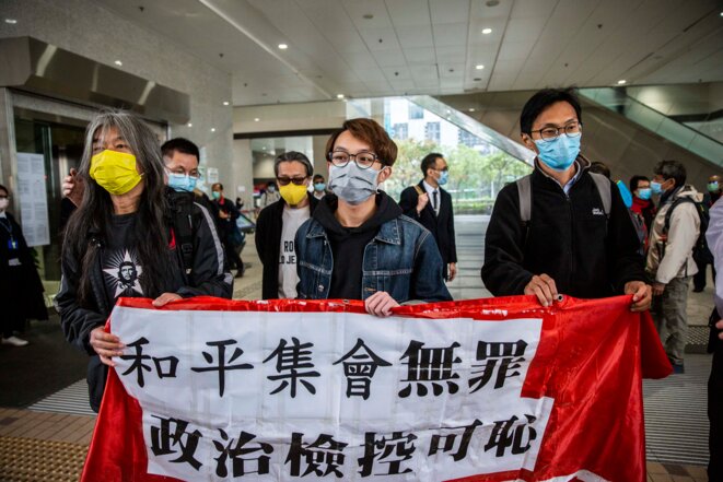 Trois des militants hongkongais poursuivis pour rassemblement illégal devant le tribunal, le 17 décembre 2020. © Isaac Lawrence/AFP