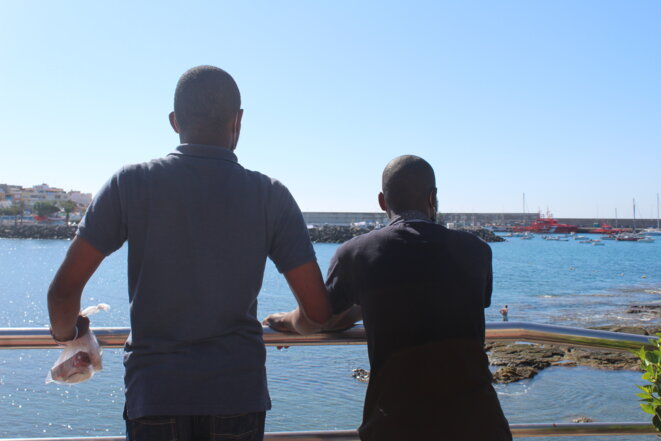 Deux migrants subsahariens observant le port d'Arguineguin, où ils ont débarqué en novembre 2020. © NB.