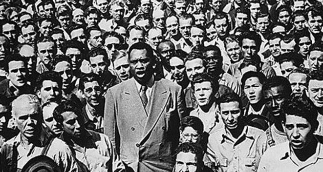 Paul Robeson en 1942, au milieu d'ouvriers d'un chantier naval aux Etats-Unis. Crédit: National Archives. Paul Robeson en 1942, au milieu d'ouvriers d'un chantier naval aux Etats-Unis. Crédit: National Archives.