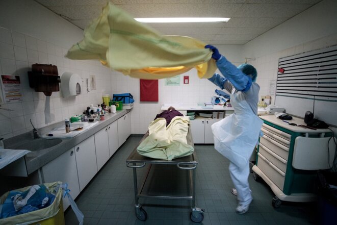 Le 29 janvier 2021, à la morgue de l'hôpital Bichat, à Paris, un membre de l'équipe médicale drape le corps d'un défunt, juste avant l'arrivée de proches. © Joel Saget / AFP