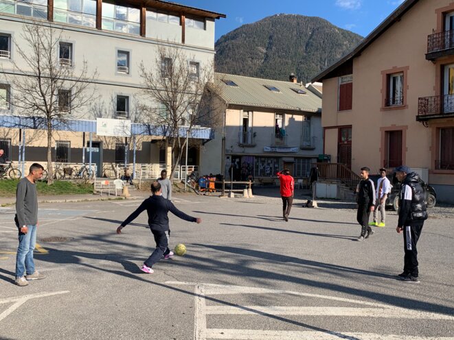 Des jeunes jouant au football devant l'entrée du refuge solidaire à Briançon. © NB
