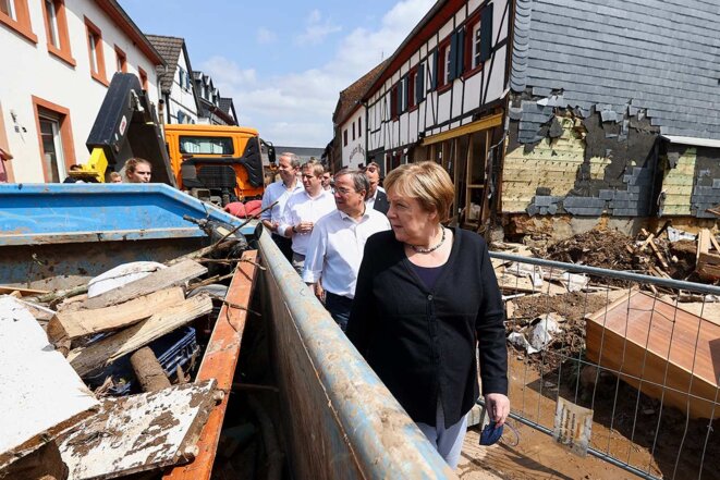 La chancelière allemande Angela Merkel avec le candidat conservateur aux élections, Armin Laschet, juste derrière elle, lors de leur déplacement à IIversheim pour constater les dégâts causés par les inondations. © Photo  Wolfgang Rattay / Reuters / Pool / via AFP