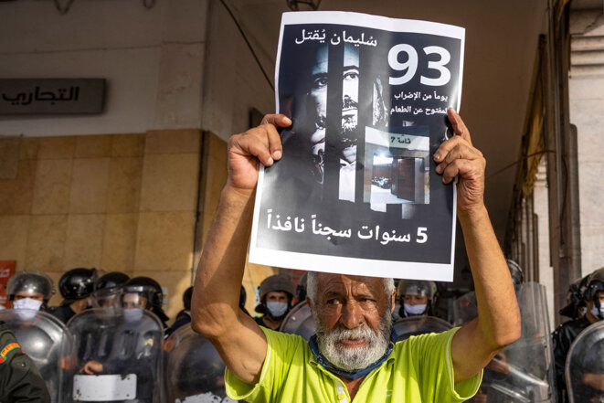 Un militant tient une banderole à l'effigie de Soulaimane Raissouni, lors de la manifestation de soutien aux journalistes emprisonnés, le 10 juillet 2021, à Rabat. © Photo Fadel Senna / AFP Un militant tient une banderole à l'effigie de Soulaimane Raissouni, lors de la manifestation de soutien aux journalistes emprisonnés, le 10 juillet 2021, à Rabat. © Photo Fadel Senna / AFP