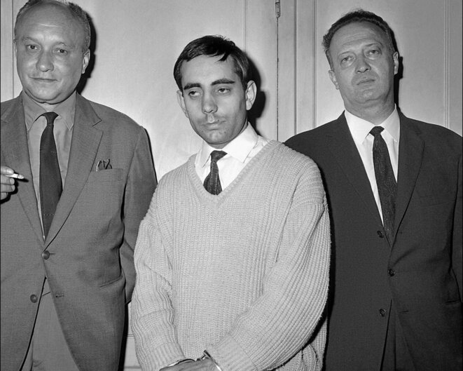 Lucien Léger, au centre, photographié menotté dans les locaux d'un commissariat de police à Paris, le 5 juillet 1964. © Photo AFP