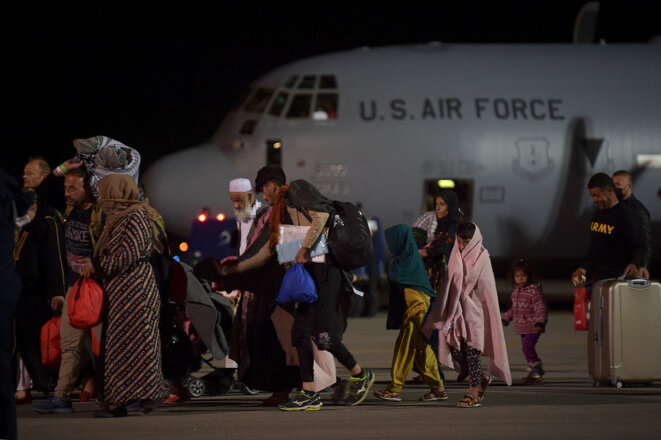 Pristina, Kosovo, le 29 août 2021. Des réfugiés afghans, ayant fuit Kaboul, à leurs arrivée à bord d’un avion de l'armée de l'air américaine. Le Kosovo a proposé d'accueillir temporairement des milliers de réfugiés afghans évacués par les forces américaines de Kaboul jusqu'à leur les demandes d'asile sont traitées. © Photo Armend Nimani / AFP