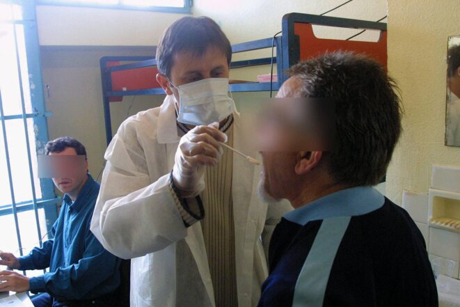 Un policier effectue un prélèvement de salive sur un détenu, en 2003. © COR / AFP Un policier effectue un prélèvement de salive sur un détenu, en 2003. © COR / AFP