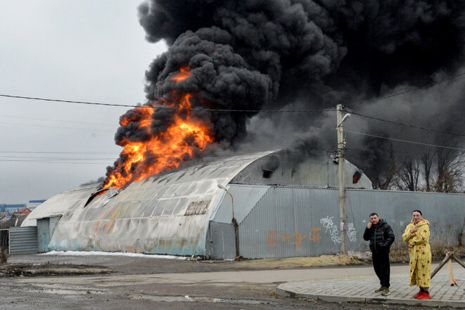 Des habitants de Kharkiv devant un bâtiment en feu après un bombardement russe, le 3 mars 2022. © Photo Sergey Bobok / AFP