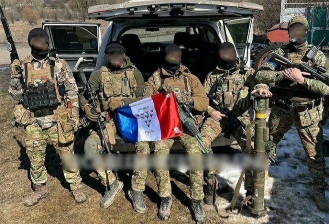 Des combattants ukrainiens, parmi lesquels des anciens soldats de la Légion étrangère, prennent la pose avec un drapeau français siglé du nom du 2e régiment étranger de parachutistes (2e REP), basé à Calvi. © Capture d'écran Telegram