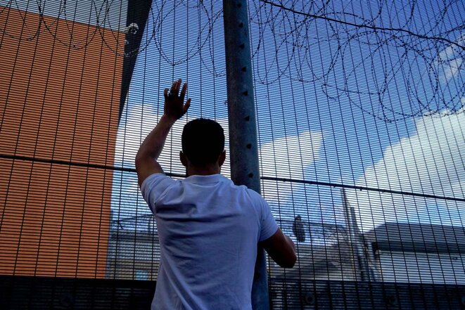 Un manifestant accroché à la clôture du centre de renvoi de Brook House près de l'aéroport de Gatwick, le 12 juin 2022. © Photo Niklas Halle’n / AFP