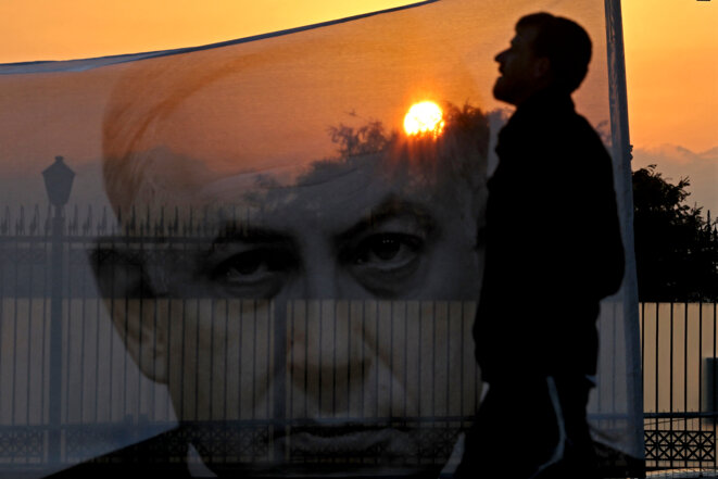 Un manifestant passe devant un portrait de Benjamin Netanyahou, le 20 février 2023 à Jérusalem. © Ahmad Gharabli / AFP