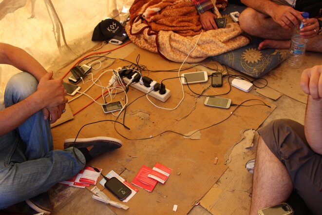 Les réfugiés rechargent leurs téléphones sous la tente Les réfugiés rechargent leurs téléphones sous la tente